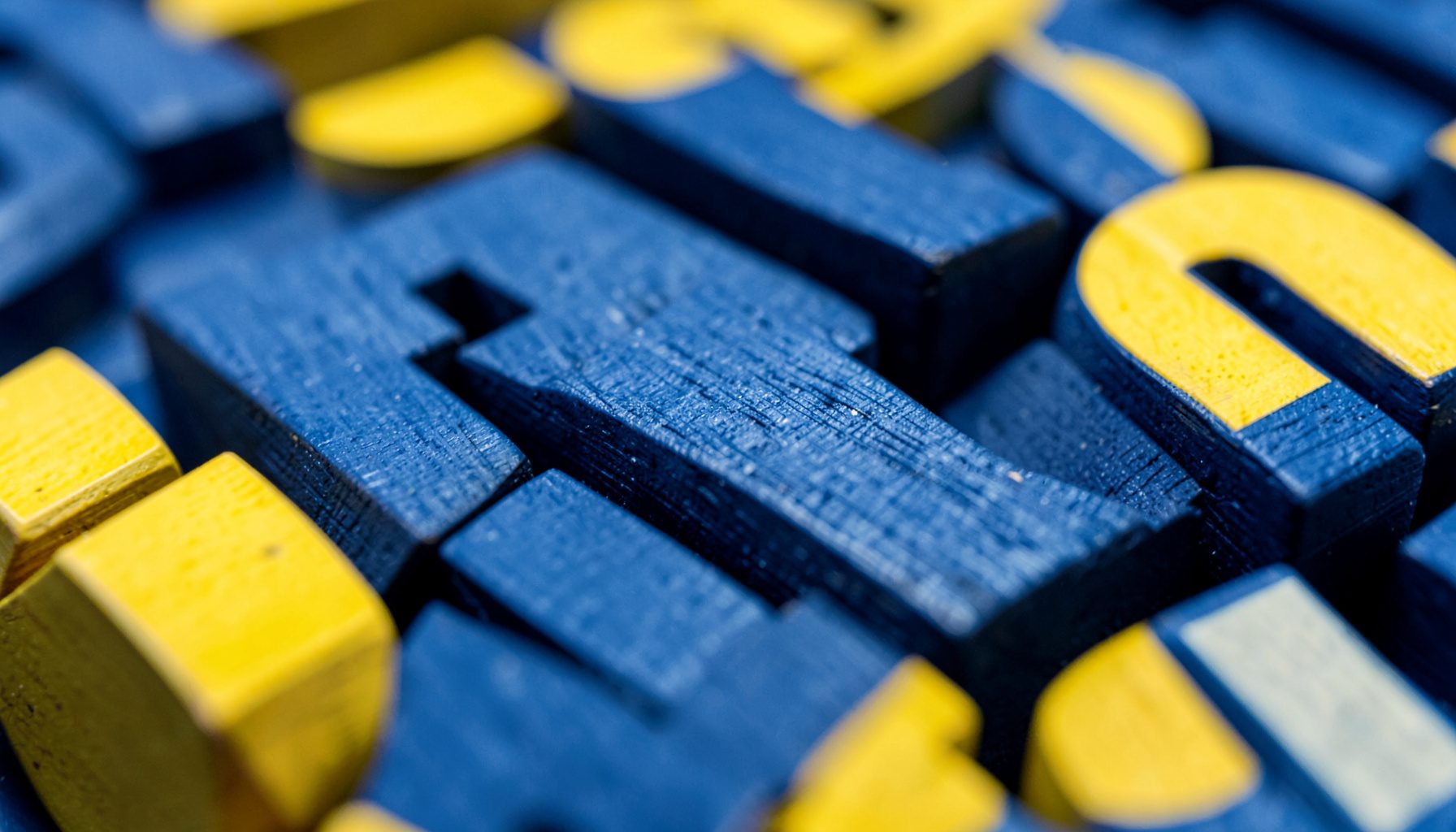 Gros plan sur des blocs alphabet en bois bleu marine et jaune, texture du bois visible