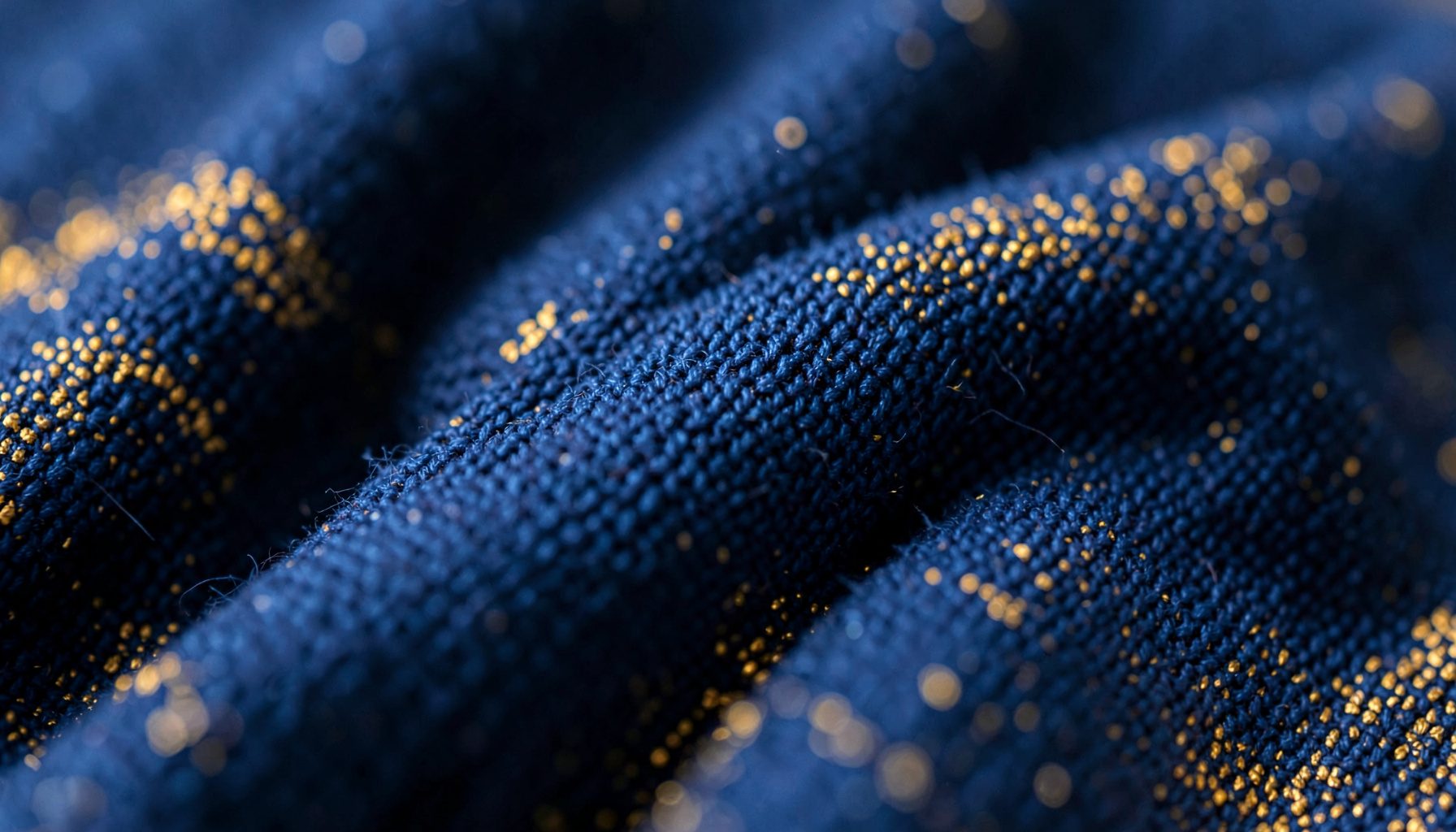 Gros plan sur un tissu tissé bleu marine et doré, texture douce et chaleureuse évoquant la confiance et la bienveillance