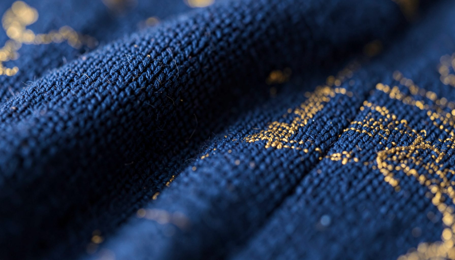 Gros plan sur un tissu tissé bleu marine et doré évoquant la couverture d'un livre pour enfants, ambiance chaleureuse et douce